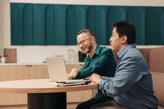 Two colleagues collaborating at a desktop computer in an office setting.